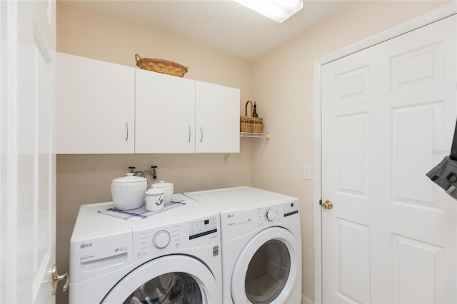 washroom featuring a textured ceiling, cabinets, and washing machine and clothes dryer