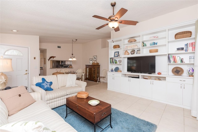 living room with ceiling fan, light tile patterned floors, and a textured ceiling