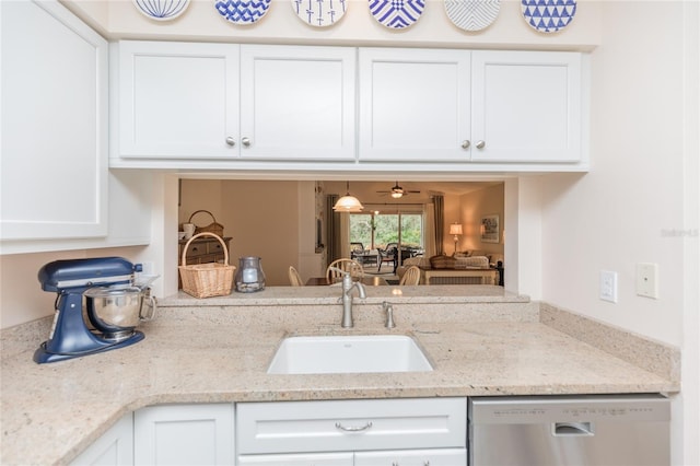 kitchen featuring light stone counters, stainless steel dishwasher, sink, and white cabinets