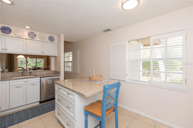 kitchen featuring sink, dishwasher, a kitchen breakfast bar, white cabinets, and light tile patterned flooring