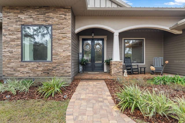 view of exterior entry with a porch and french doors