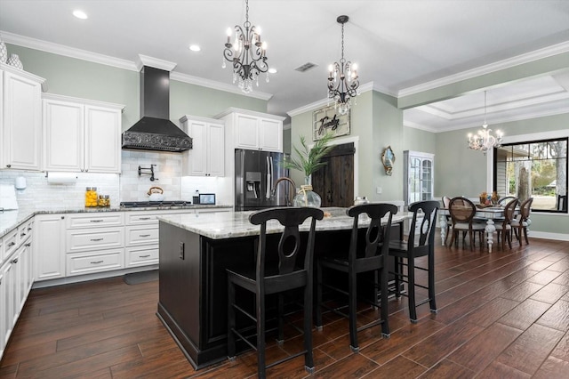 kitchen featuring a breakfast bar, an island with sink, white cabinetry, stainless steel appliances, and custom range hood