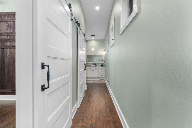 corridor with dark wood-type flooring and a barn door