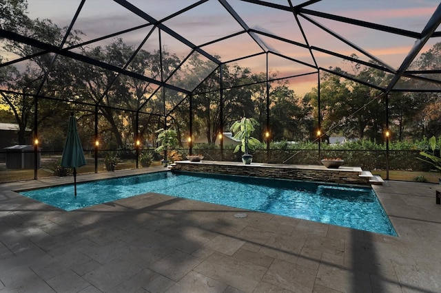 pool at dusk with a patio area and glass enclosure