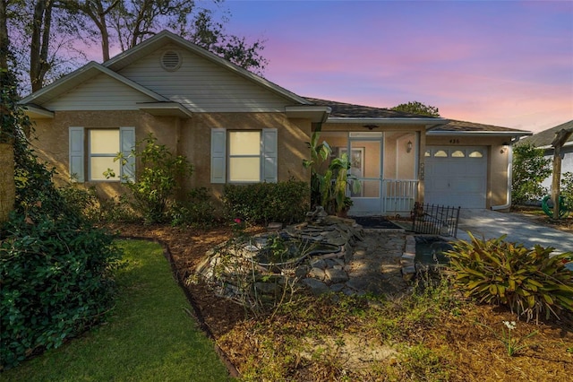 ranch-style home with stucco siding, an attached garage, driveway, and a sunroom