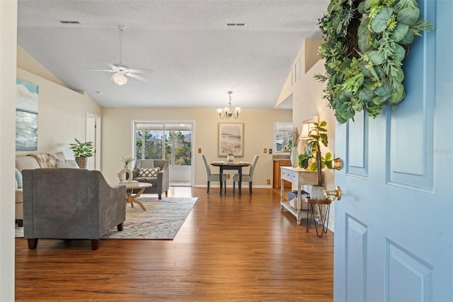 entryway with visible vents, baseboards, lofted ceiling, wood finished floors, and a textured ceiling