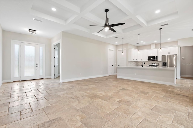 unfurnished living room with beamed ceiling, ceiling fan, coffered ceiling, and sink