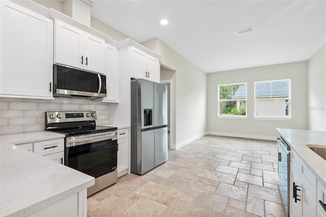 kitchen featuring white cabinetry, appliances with stainless steel finishes, light stone counters, and tasteful backsplash