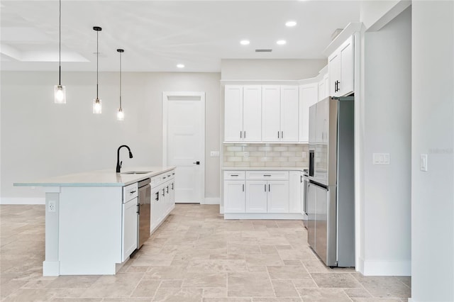 kitchen featuring stainless steel appliances, decorative light fixtures, a center island with sink, and white cabinets