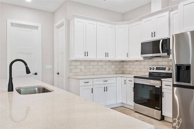 kitchen featuring stainless steel appliances, white cabinetry, sink, and backsplash