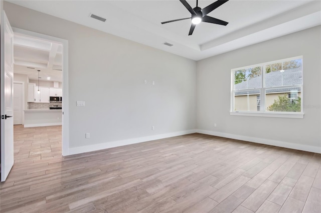 unfurnished room with ceiling fan, a raised ceiling, and light hardwood / wood-style flooring