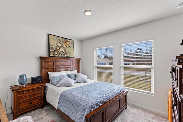 bedroom with light colored carpet and a textured ceiling