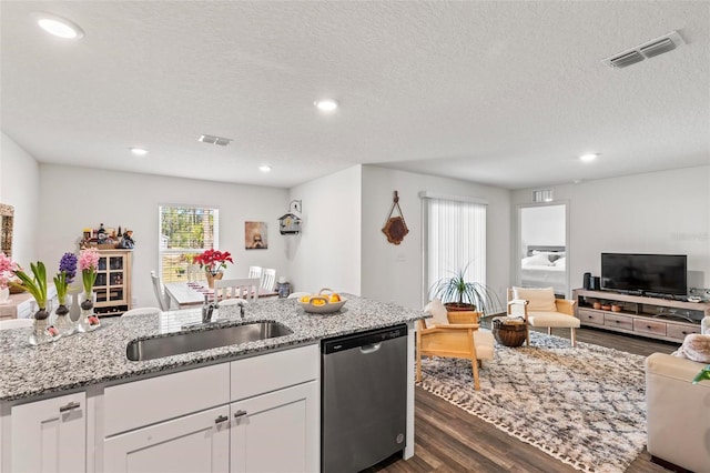 kitchen with dishwasher, sink, white cabinets, light stone counters, and dark wood-type flooring