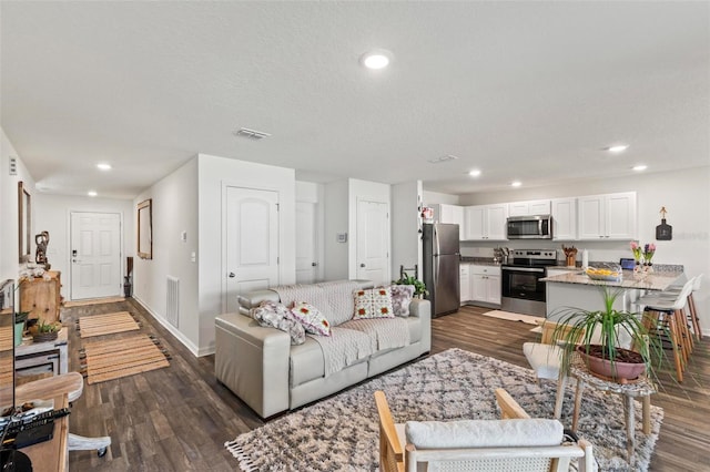 living room with dark wood-type flooring and a textured ceiling