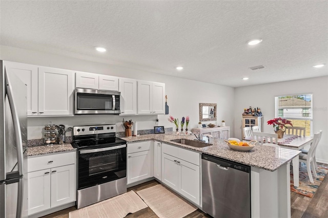 kitchen featuring appliances with stainless steel finishes, kitchen peninsula, and white cabinets