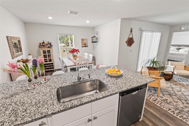 kitchen with white cabinetry, stainless steel dishwasher, dark hardwood / wood-style floors, and light stone counters