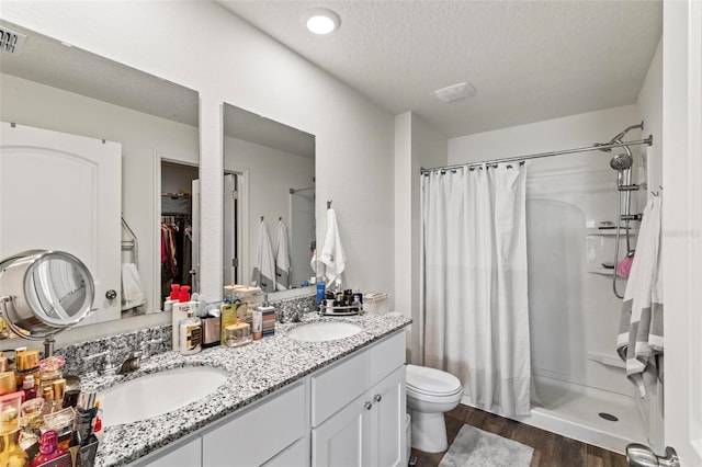 bathroom with hardwood / wood-style flooring, vanity, a textured ceiling, curtained shower, and toilet