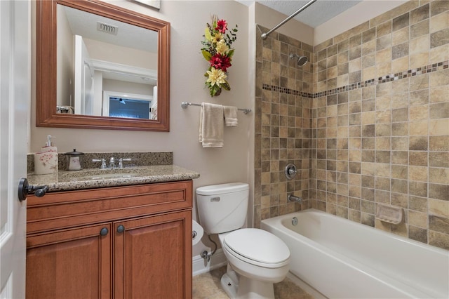 full bathroom featuring vanity, tiled shower / bath, and toilet