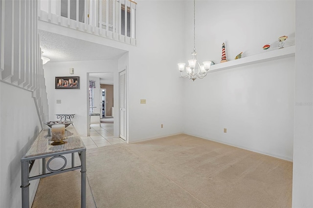 carpeted empty room featuring a towering ceiling and an inviting chandelier