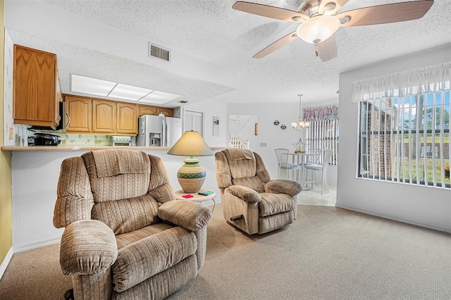 living room featuring light carpet, ceiling fan with notable chandelier, and a textured ceiling