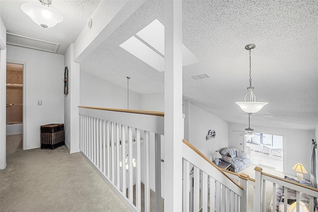 hall featuring light carpet and a textured ceiling