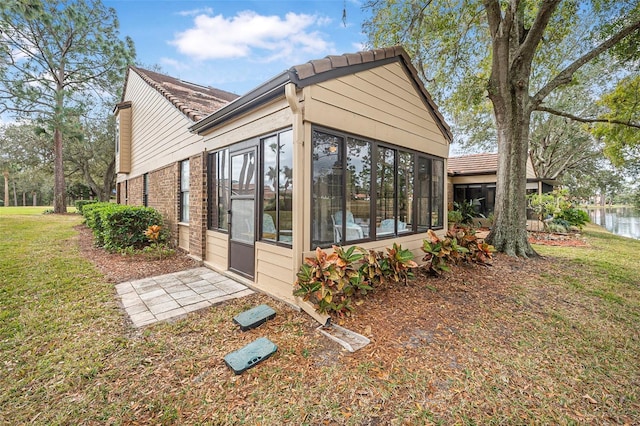 view of side of home with a sunroom and a lawn