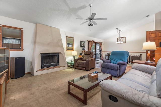 carpeted living room with ceiling fan, a large fireplace, vaulted ceiling, and a textured ceiling