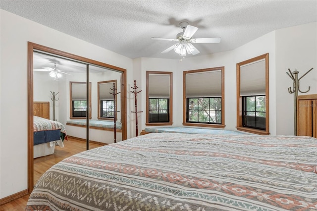 bedroom featuring ceiling fan, light hardwood / wood-style flooring, a closet, and a textured ceiling