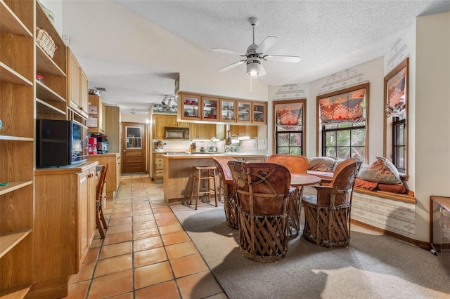 tiled dining space featuring a textured ceiling and ceiling fan