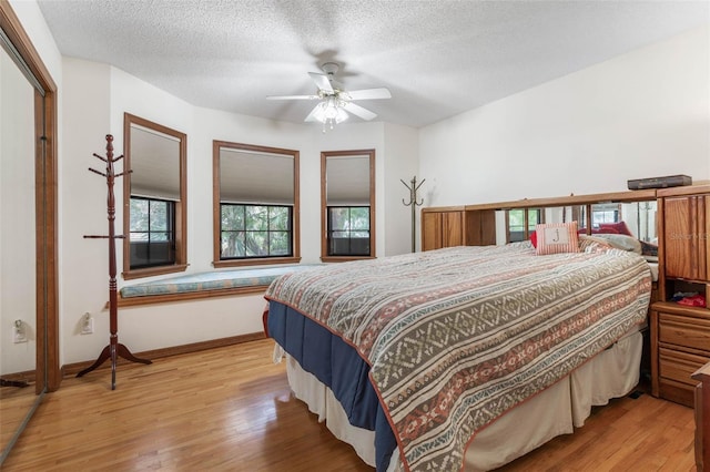 bedroom featuring ceiling fan, light hardwood / wood-style floors, and a textured ceiling