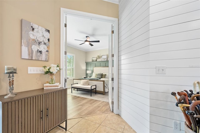 hallway with ornamental molding and light tile patterned floors