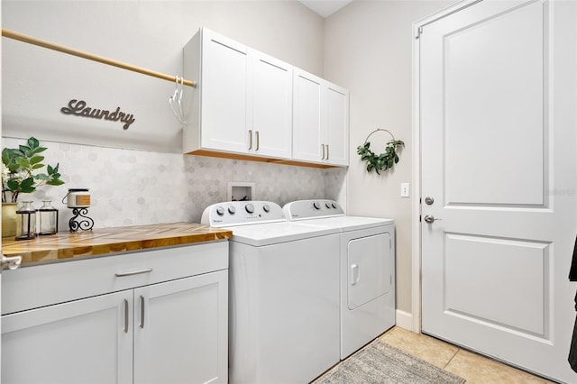 laundry room with light tile patterned floors, washer and clothes dryer, and cabinets