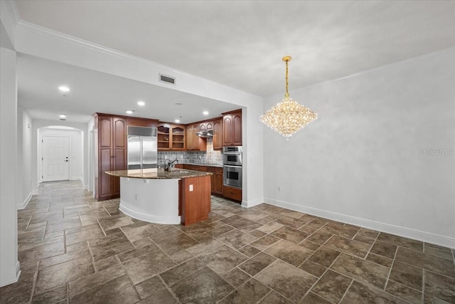 kitchen with appliances with stainless steel finishes, stone countertops, tasteful backsplash, sink, and a center island with sink