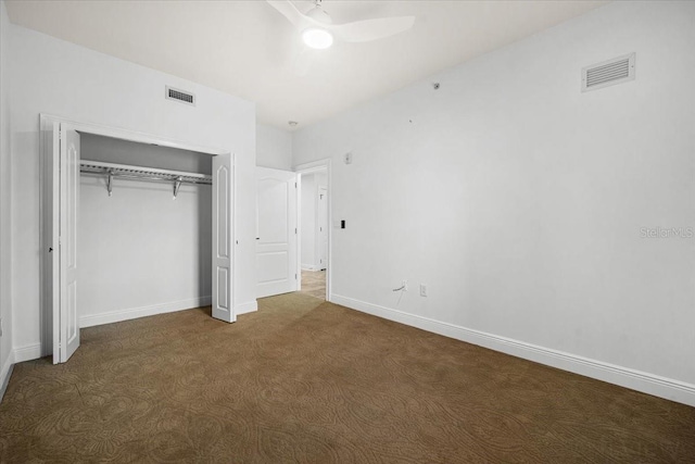 unfurnished bedroom featuring dark colored carpet, ceiling fan, and a closet