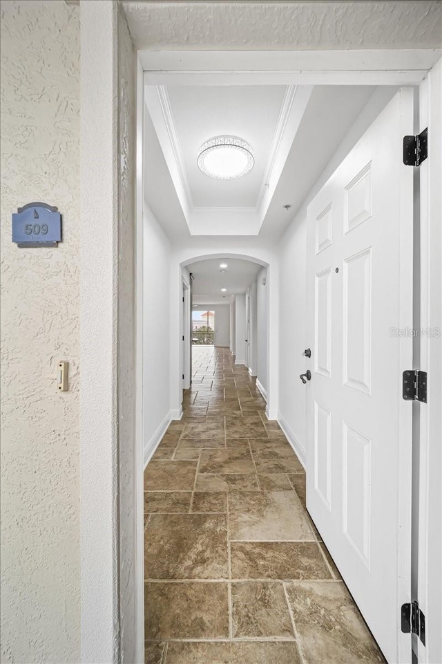 hall with crown molding and a raised ceiling