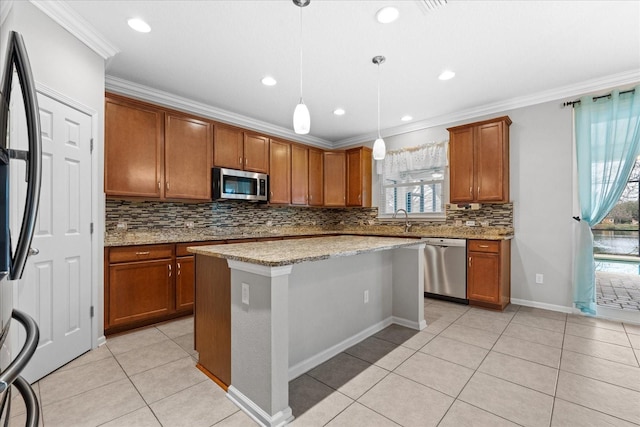 kitchen featuring light stone counters, a center island, hanging light fixtures, ornamental molding, and appliances with stainless steel finishes