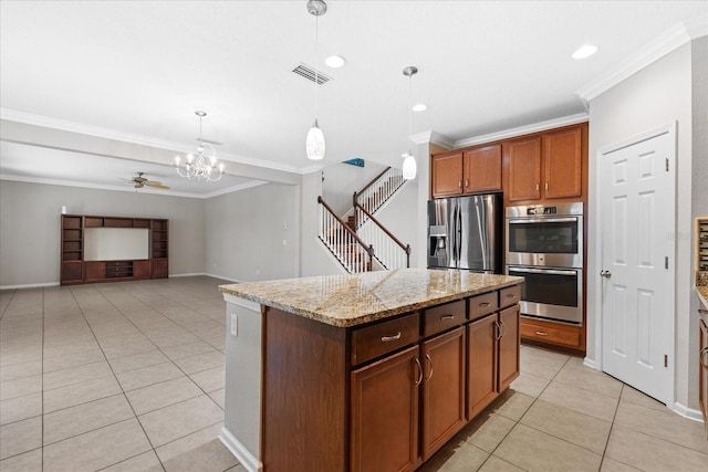 kitchen with light tile patterned flooring, hanging light fixtures, a center island, stainless steel appliances, and light stone countertops