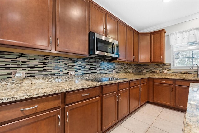 kitchen with tasteful backsplash, black electric stovetop, light tile patterned floors, light stone counters, and crown molding