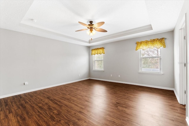 unfurnished room featuring dark hardwood / wood-style floors, a textured ceiling, and a tray ceiling