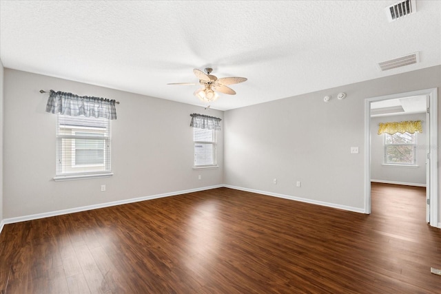 unfurnished room with dark wood-type flooring, ceiling fan, plenty of natural light, and a textured ceiling