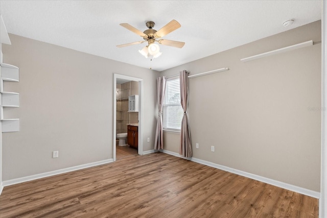 unfurnished bedroom featuring wood-type flooring, ceiling fan, and ensuite bath