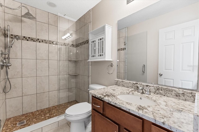 bathroom featuring vanity, a tile shower, a textured ceiling, and toilet