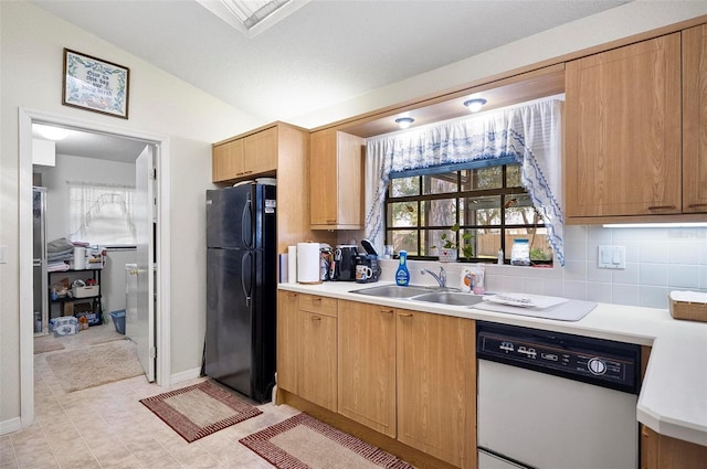 kitchen with lofted ceiling, sink, black fridge, dishwasher, and decorative backsplash