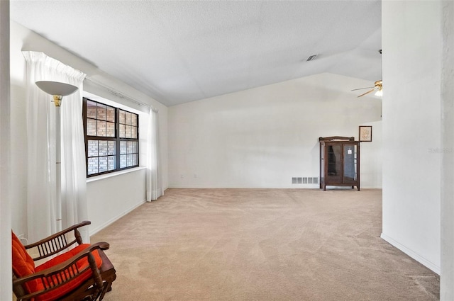 carpeted spare room with vaulted ceiling, ceiling fan, and a textured ceiling