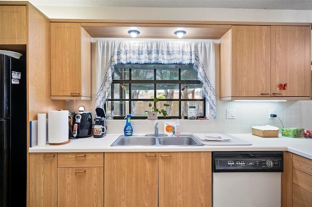 kitchen with white dishwasher, sink, tasteful backsplash, and black fridge