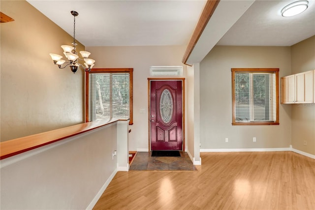 foyer with a wealth of natural light, a chandelier, and light wood-type flooring