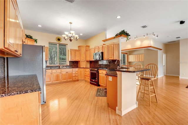 kitchen with pendant lighting, a breakfast bar, appliances with stainless steel finishes, tasteful backsplash, and kitchen peninsula