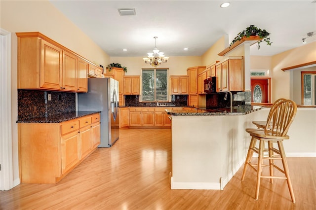 kitchen featuring stainless steel refrigerator with ice dispenser, pendant lighting, light hardwood / wood-style floors, and kitchen peninsula