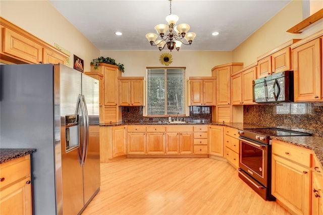 kitchen with appliances with stainless steel finishes, light brown cabinetry, and decorative light fixtures