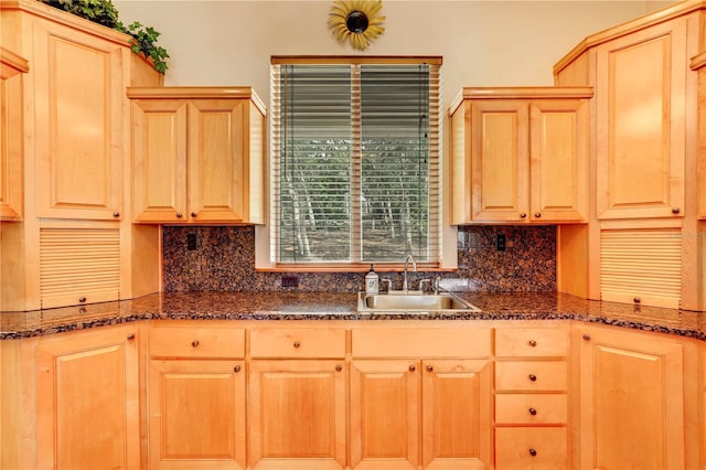 kitchen with light brown cabinetry, sink, decorative backsplash, and dark stone countertops